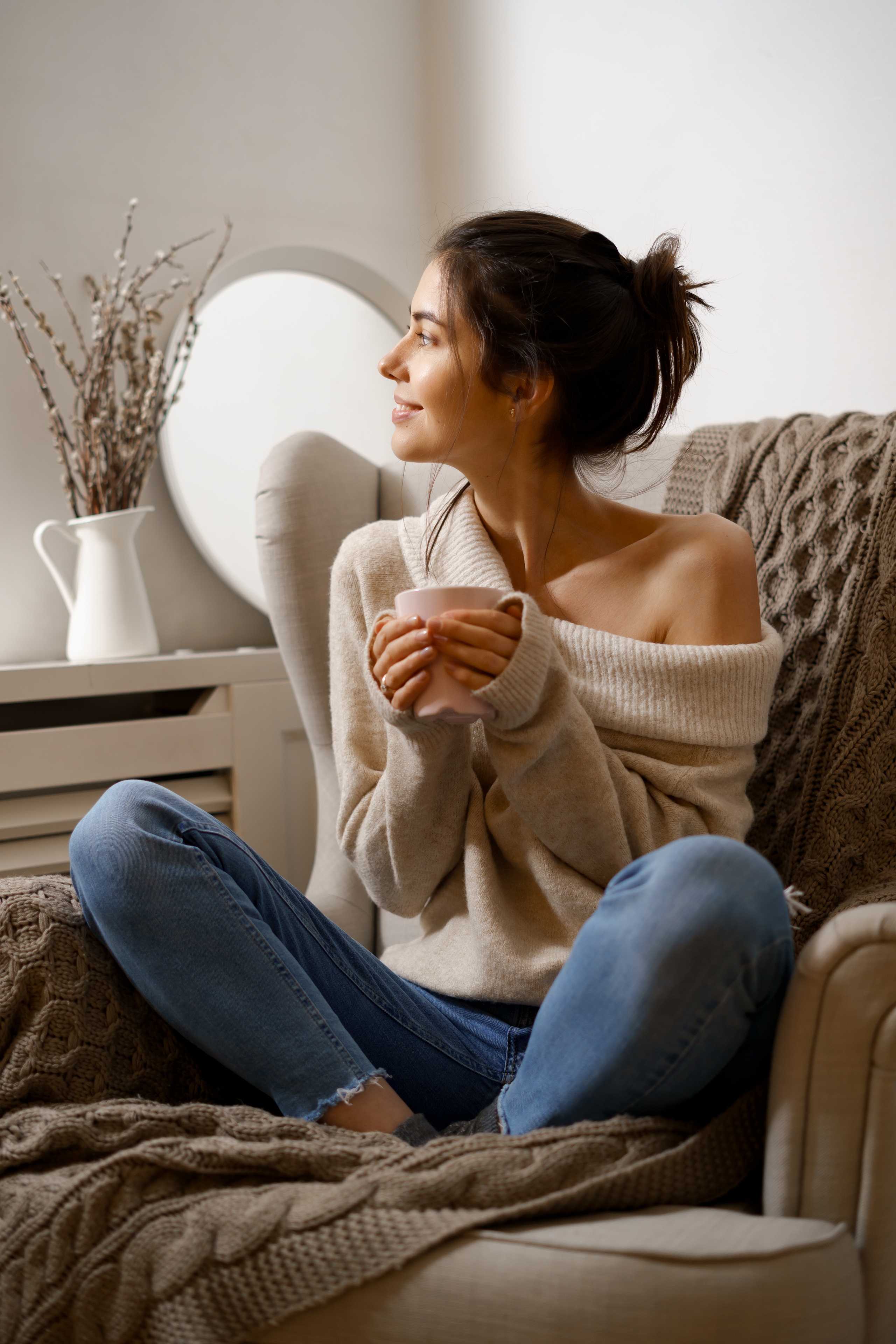 femme sereine assise dans un fauteuil tenant une tasse dans les mains